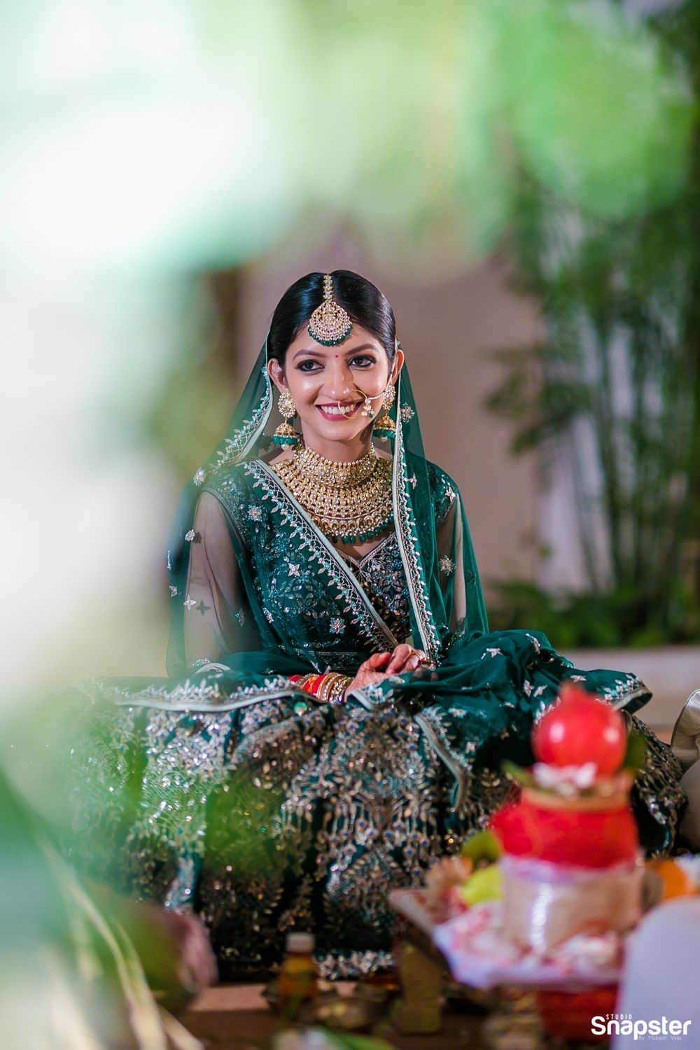 Photo of A bride in a green lehenga and oversized mangtikka on her wedding day