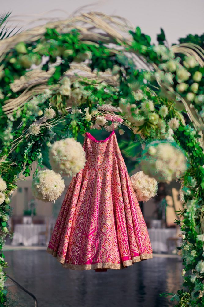 Photo of bright pink bridal lehenga hung on entrance way