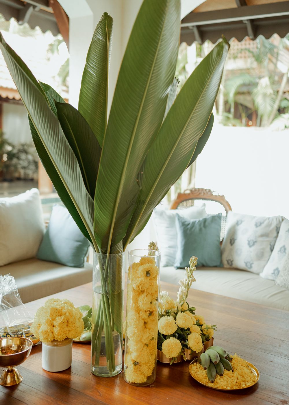 Photo of Stunning yet simple centerpiece idea with banana leaves and yellow marigold flowers for at home event