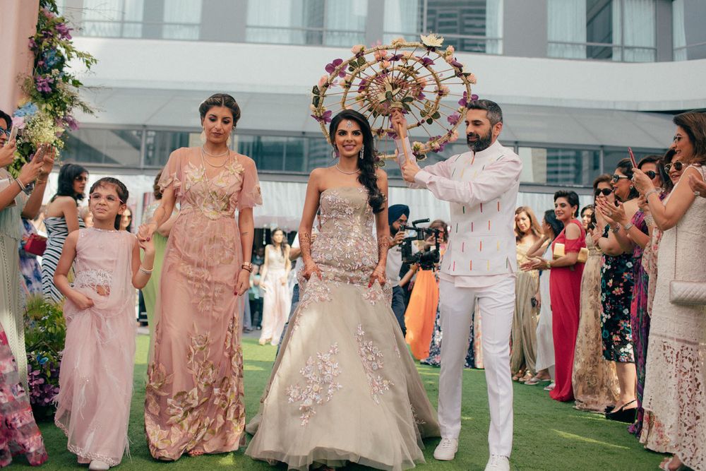 Photo of Bride entering mehendi with brother holding floral umbrella