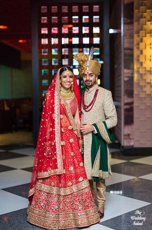 Photo of Red bridal lehenga with the groom in emerald