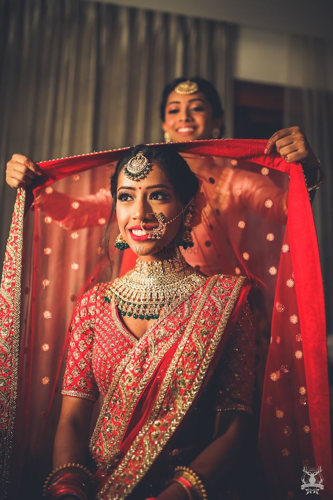 Photo of Bride with sister placing lehenga on head shot