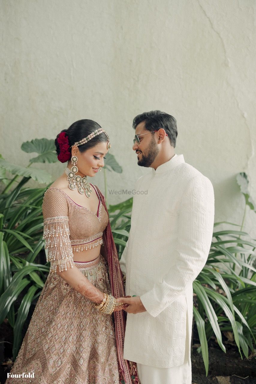 Photo of Lovely couple shot with bride wearing a stunning lehenga with a statement blouse with tassels