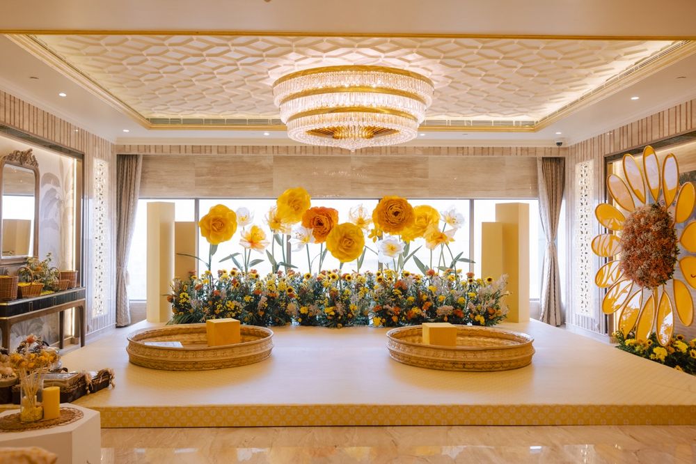 Photo of Oversized yellow floral decor backdrop for a haldi ceremony with gold urlis