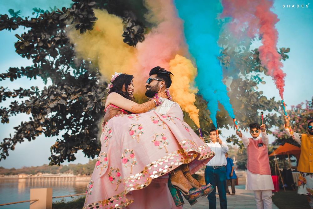 Photo of A groom lifting a bride for their mehndi entry, amidst smoke bombs