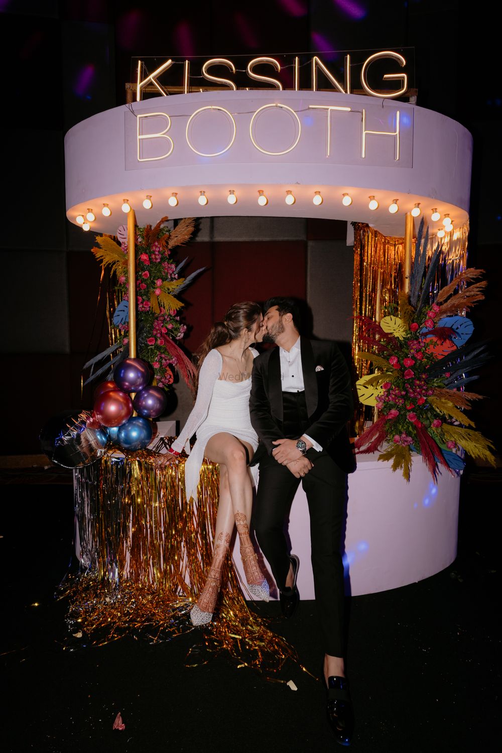 Photo of Fun capture of the bride and groom kissing at the kissing booth