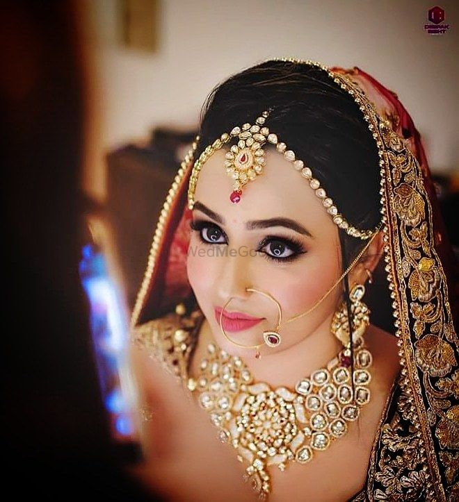 Photo of A bride with peach and gold jewelry poses for the camera.