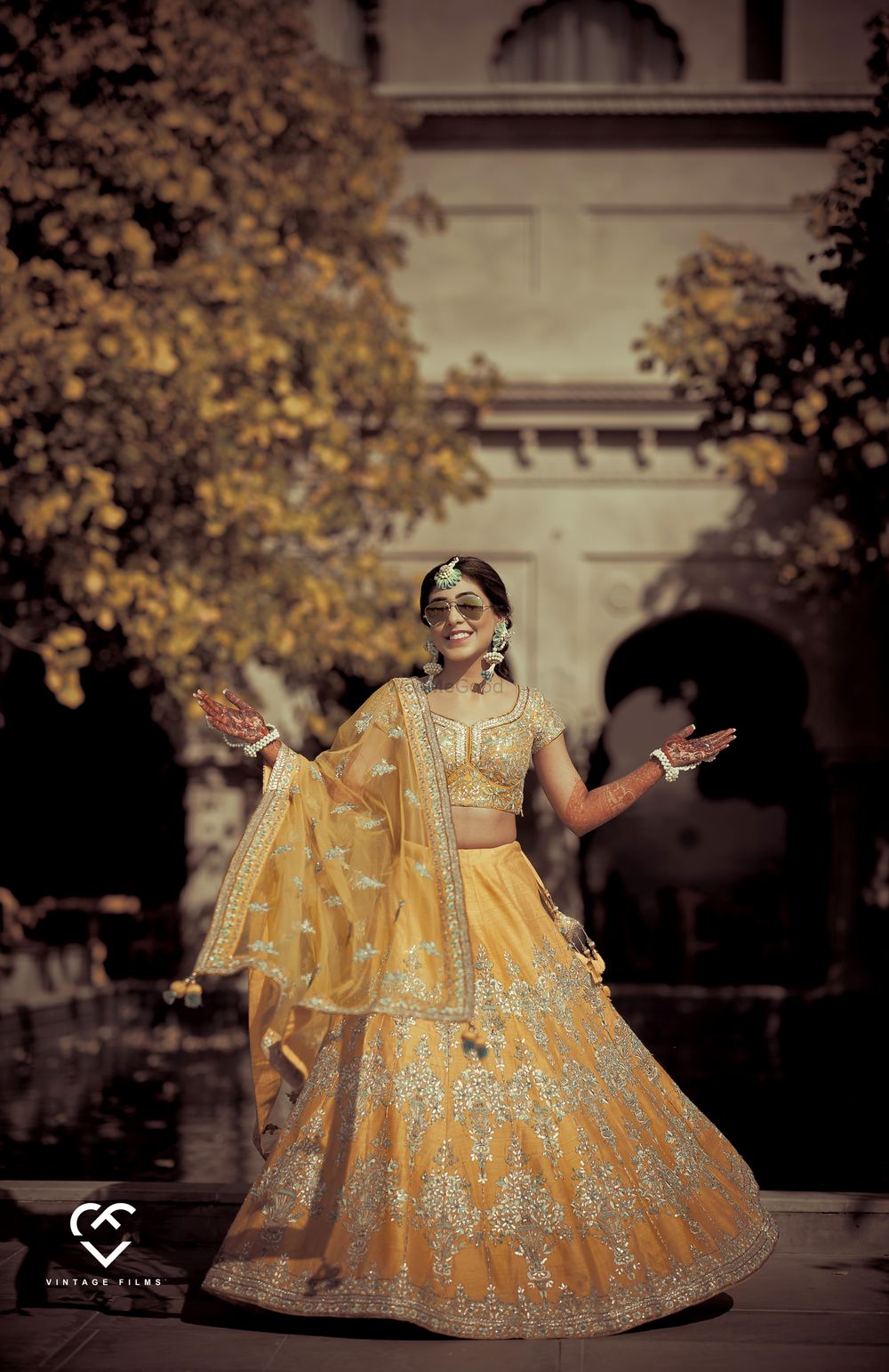 Photo of A bride in a yellow lehenga and floral jewellery for her mehendi ceremony