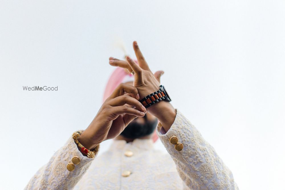 Photo of Getting ready shot of a groom wearing his watch