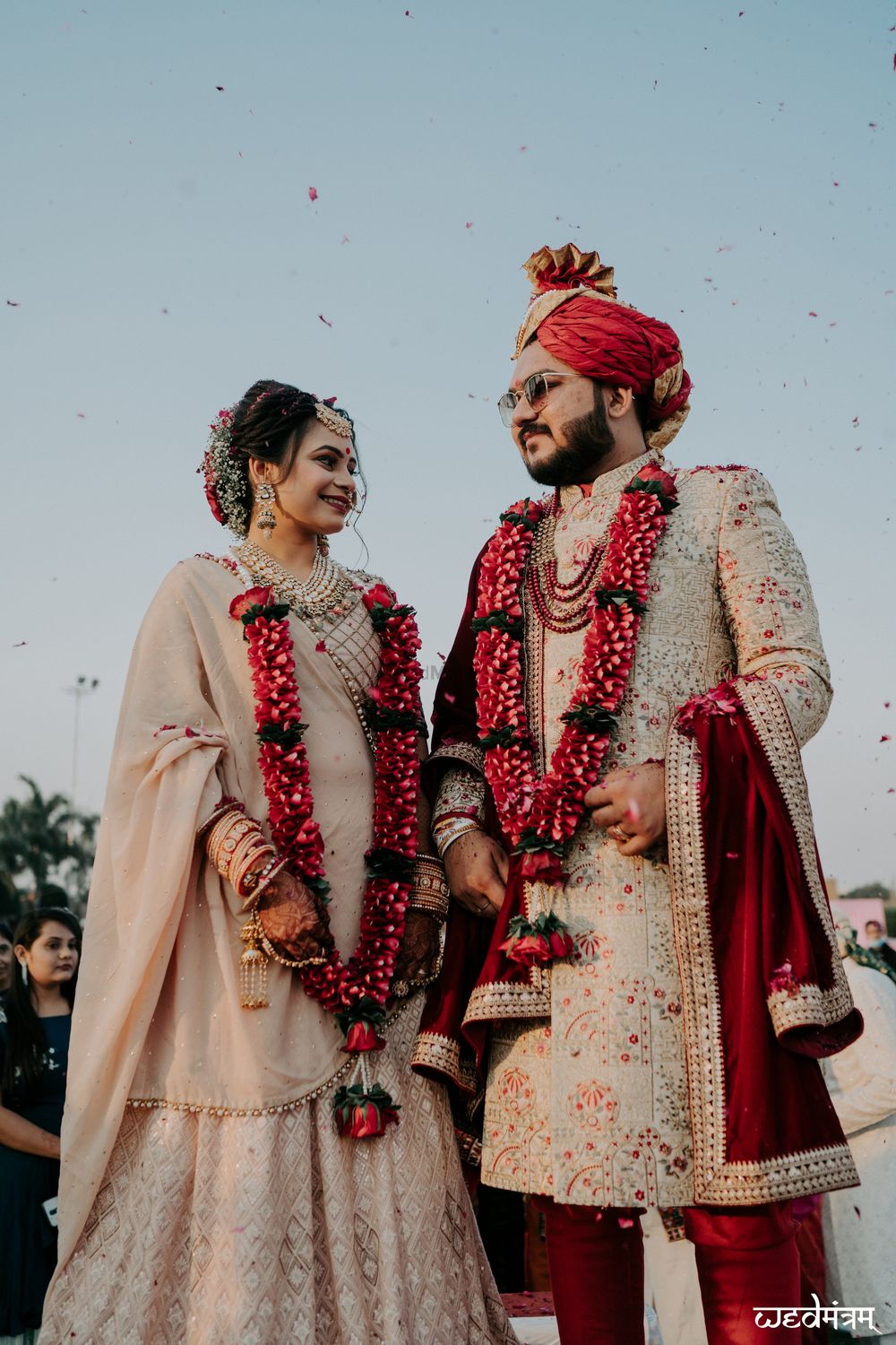 Photo of matching bride and groom with contrasting jaimalas