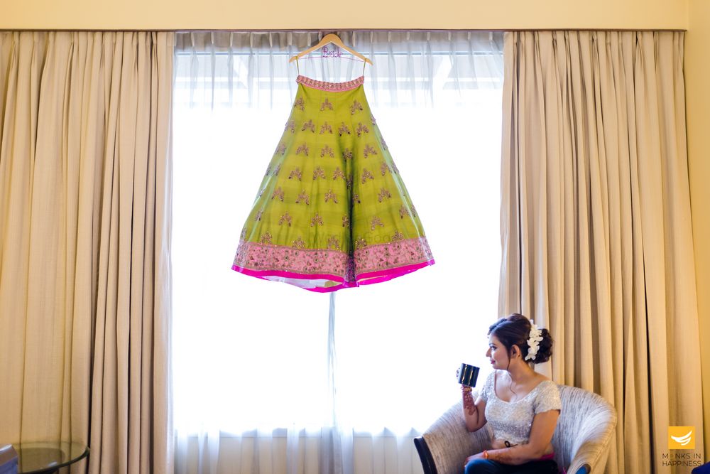 Photo of Bride sipping coffee with lehenga on hanger