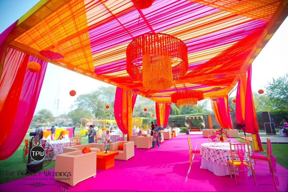 Photo of fuschia and orange theme mehendi decor with floral chandeliers