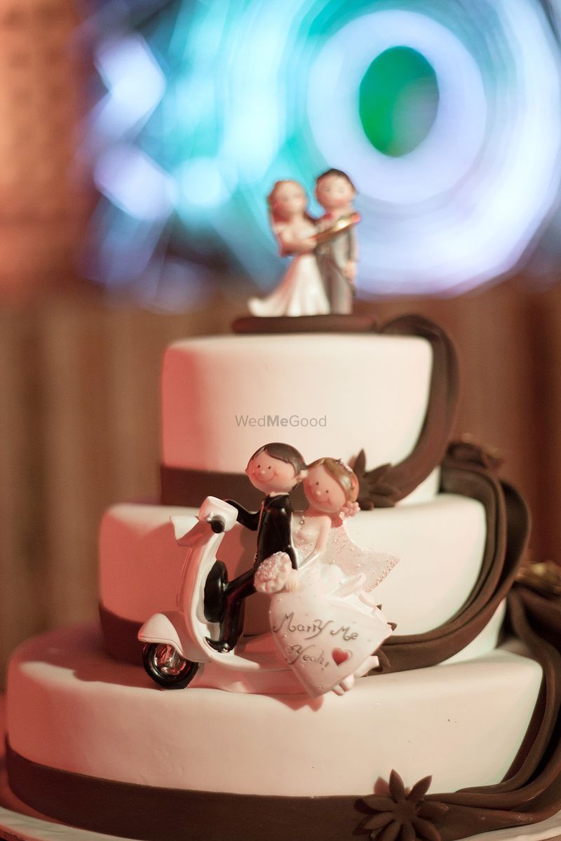 Photo of Cute wedding cake with couple portrait on scooter