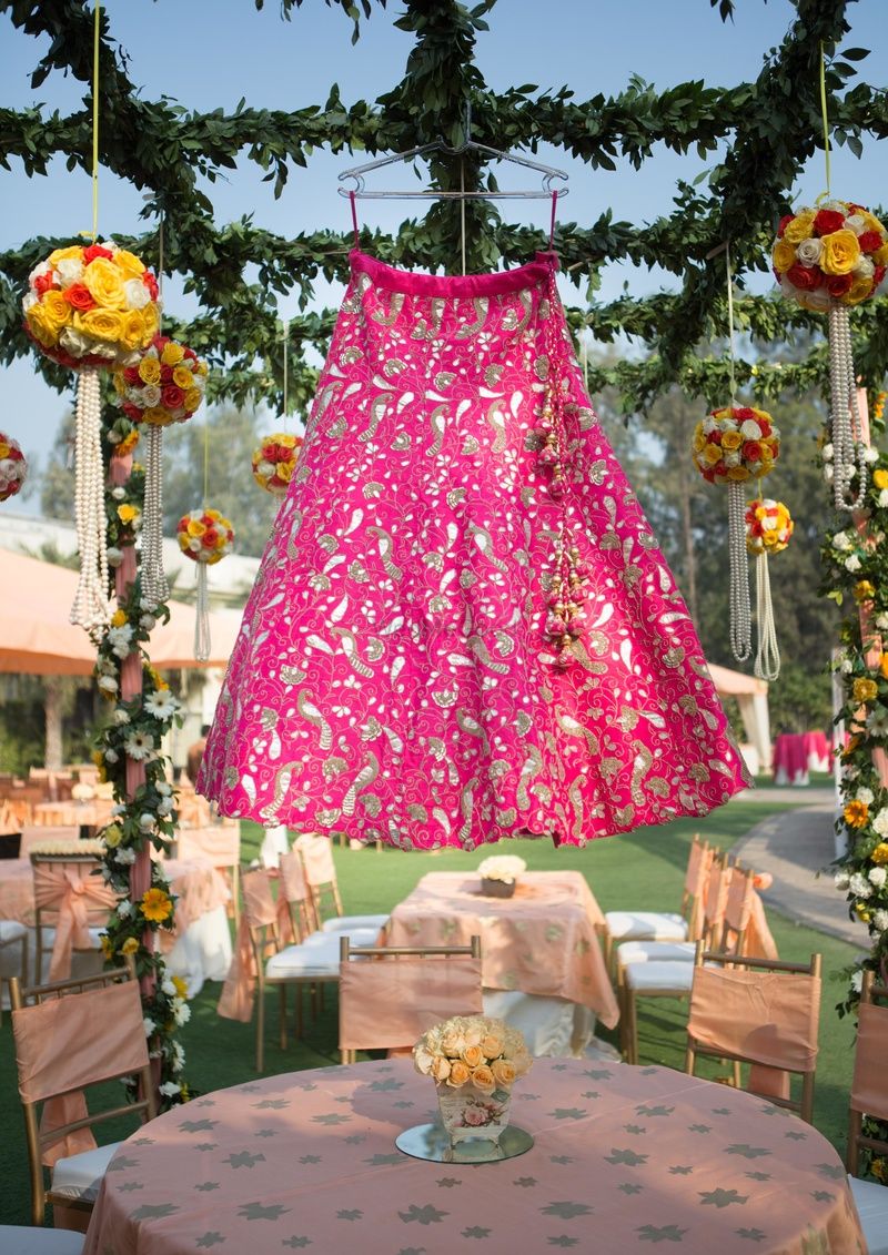 Photo of Bright pink and gold lehenga on hanger outdoors
