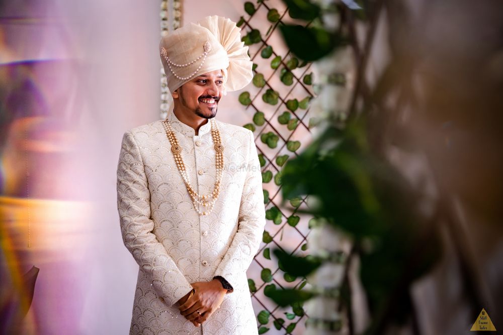 Photo of monotone groom in white with gold necklace