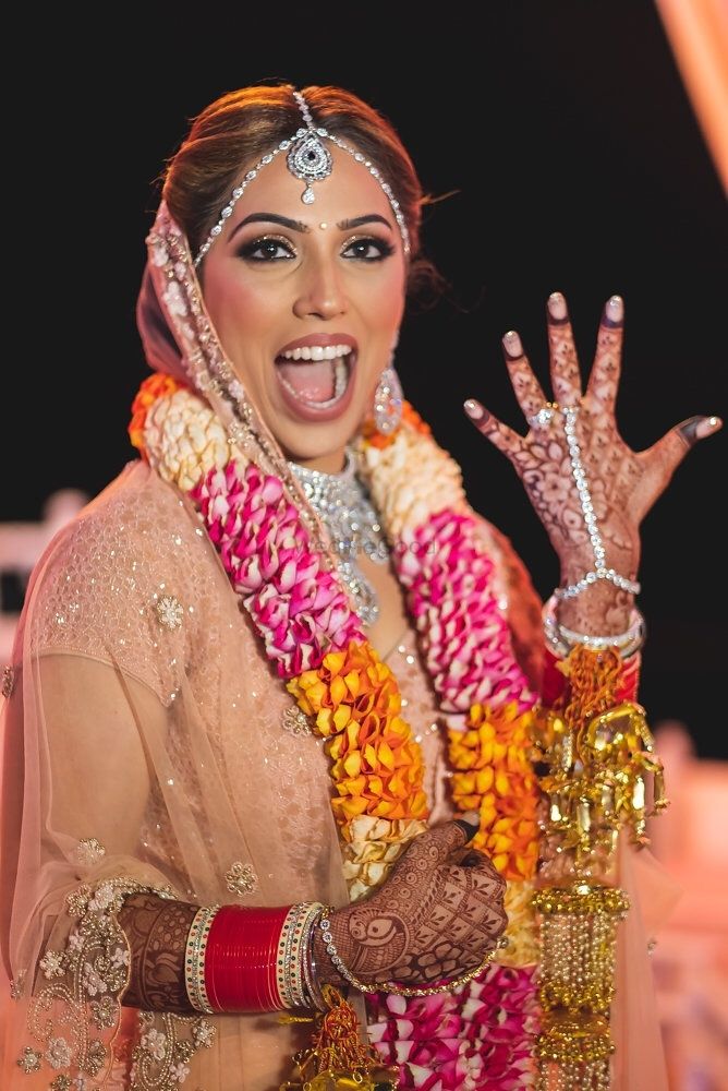 Photo of A bride in pink lehenga with unique jaimala