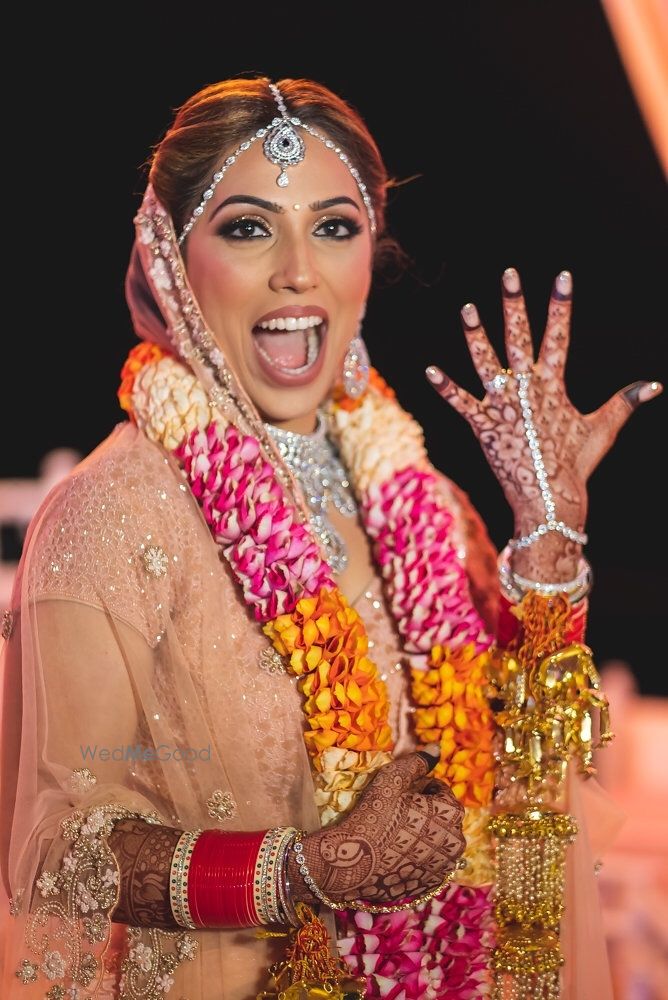 Photo of A bride in pink lehenga with unique jaimala