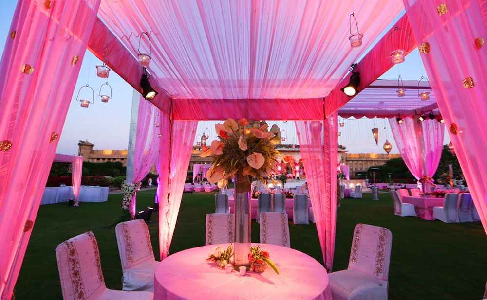 Photo of table centerpieces tall with pink drapes all around