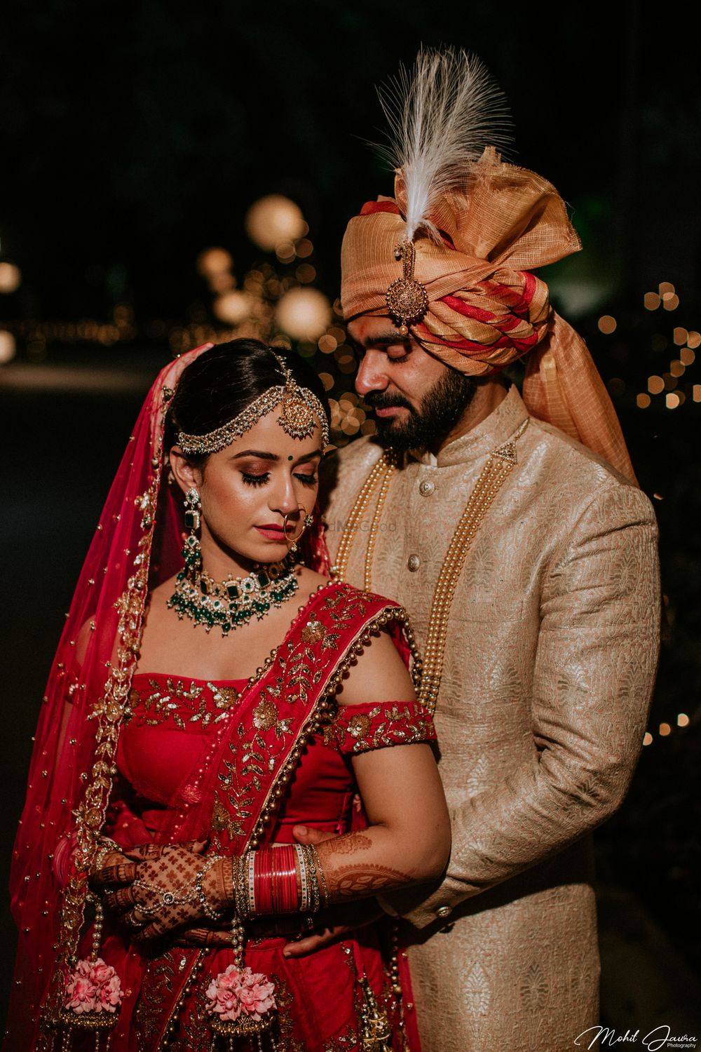 Photo of A bride in red lehenga with floral kalire ppsing with her husband on their wedding day