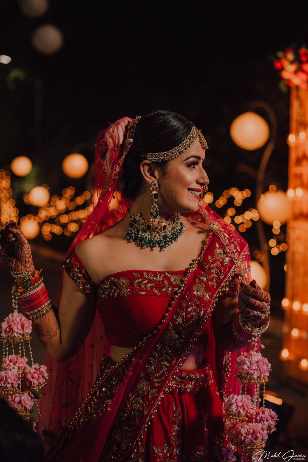 Photo of A bride in a red lehenga with offshoulder blouse  and floral kalire on her wedding day