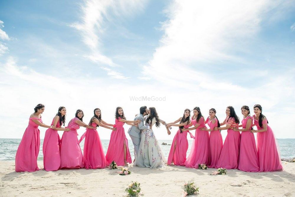 Photo of Couple kissing with matching bridesmaids in beach wedding