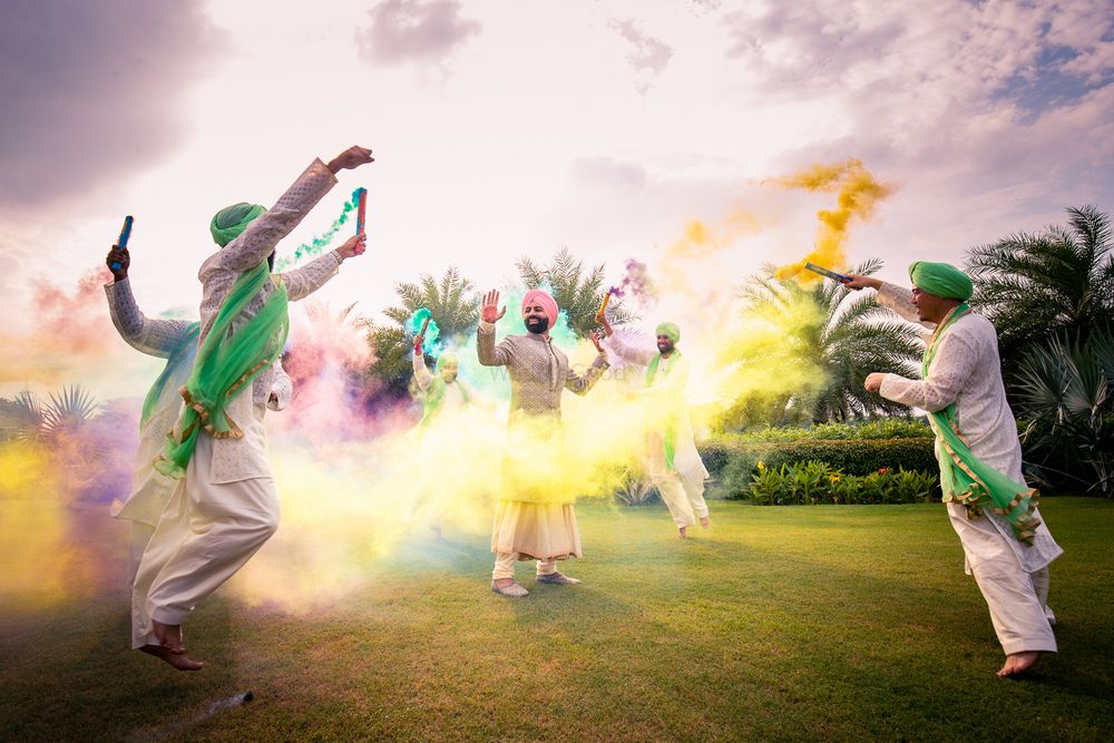 Photo of A group of groomsmen dancing with smoke bombs with the groom in the centre.