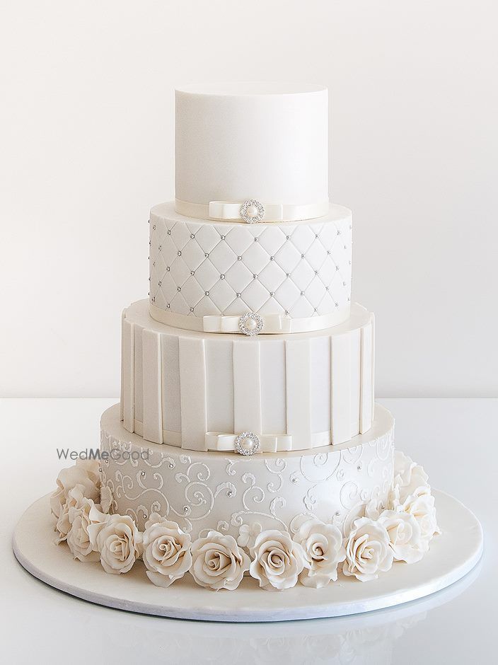 Photo of 4 tiered white wedding cake with roses