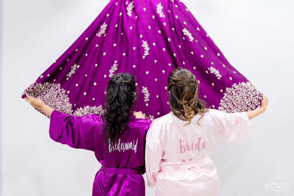 Photo of Bride with bridesmaid getting ready in robe