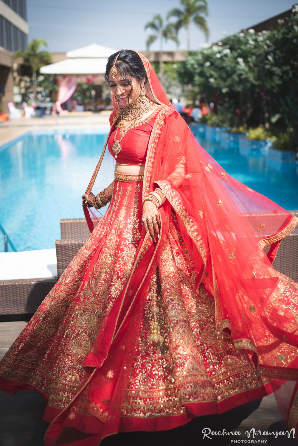 Photo of A bride in a red and gold lehenga with double dupatta, twirling on her wedding day