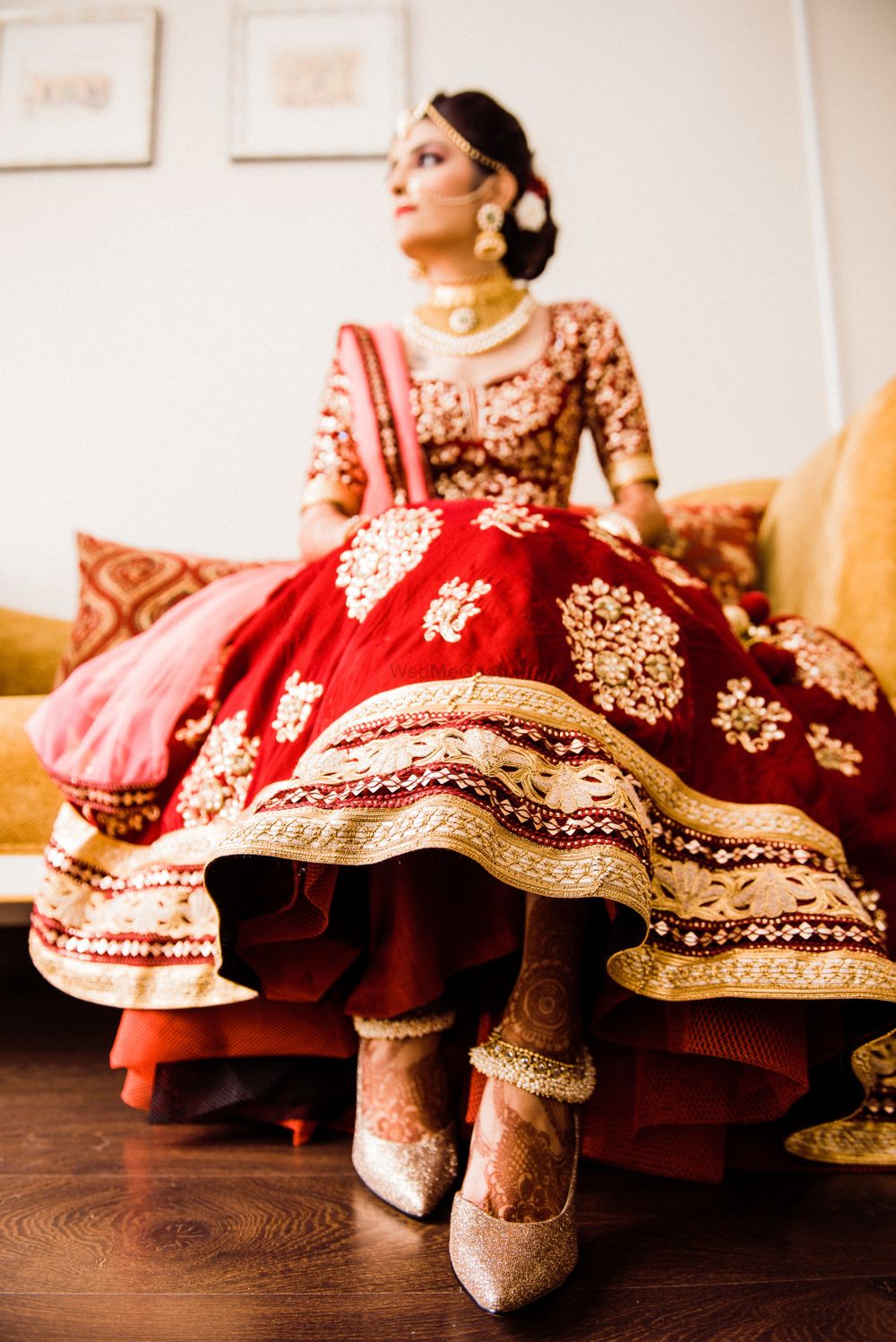 Photo of wedding day bridal portrait with bride showing off lehenga and shoes