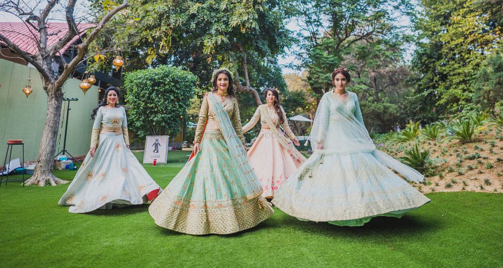 Photo of Twirling bride with bridesmaids in Pastel lehengas