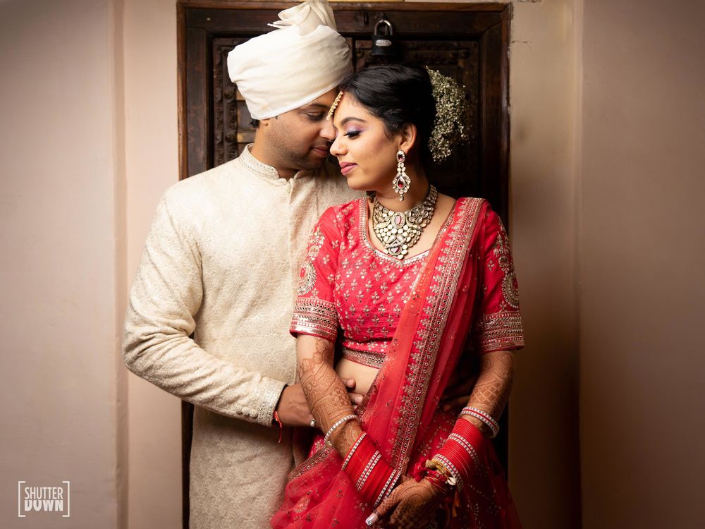 Photo of A bride and groom in red and beige attires for their wedding