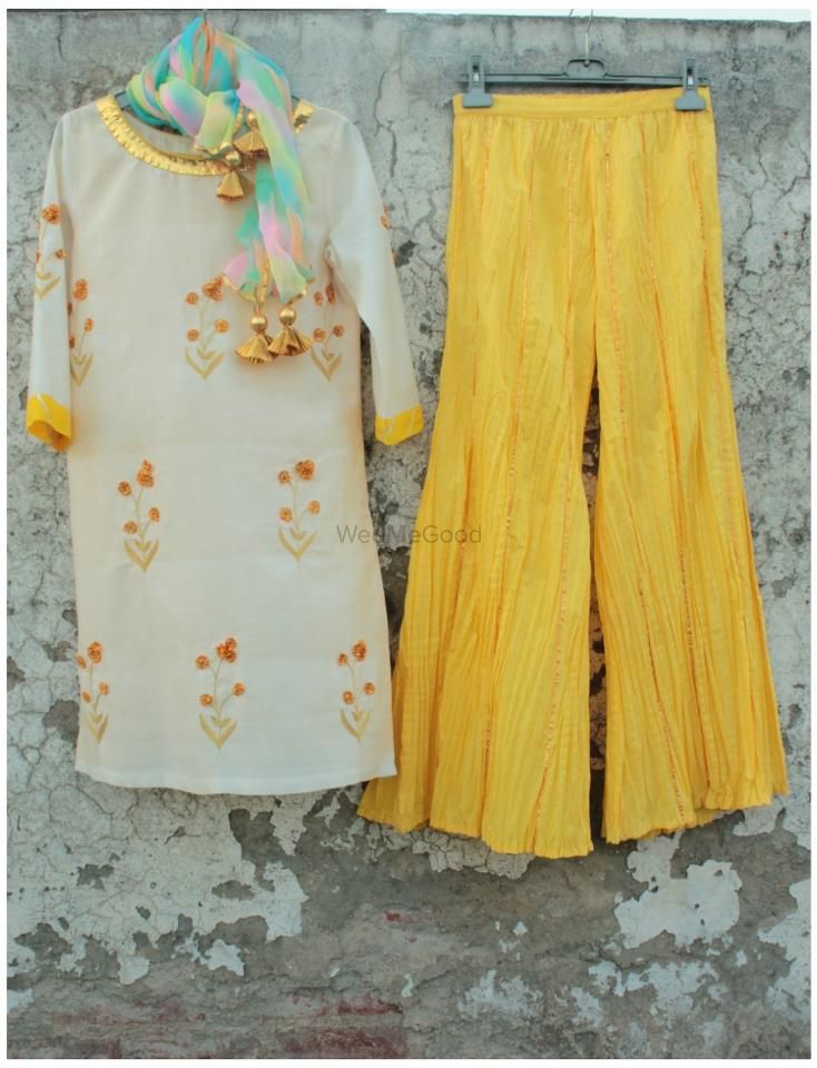 Photo of wide legged pallazo pants in yellow with white kurta and gota work. tie dye dupatta