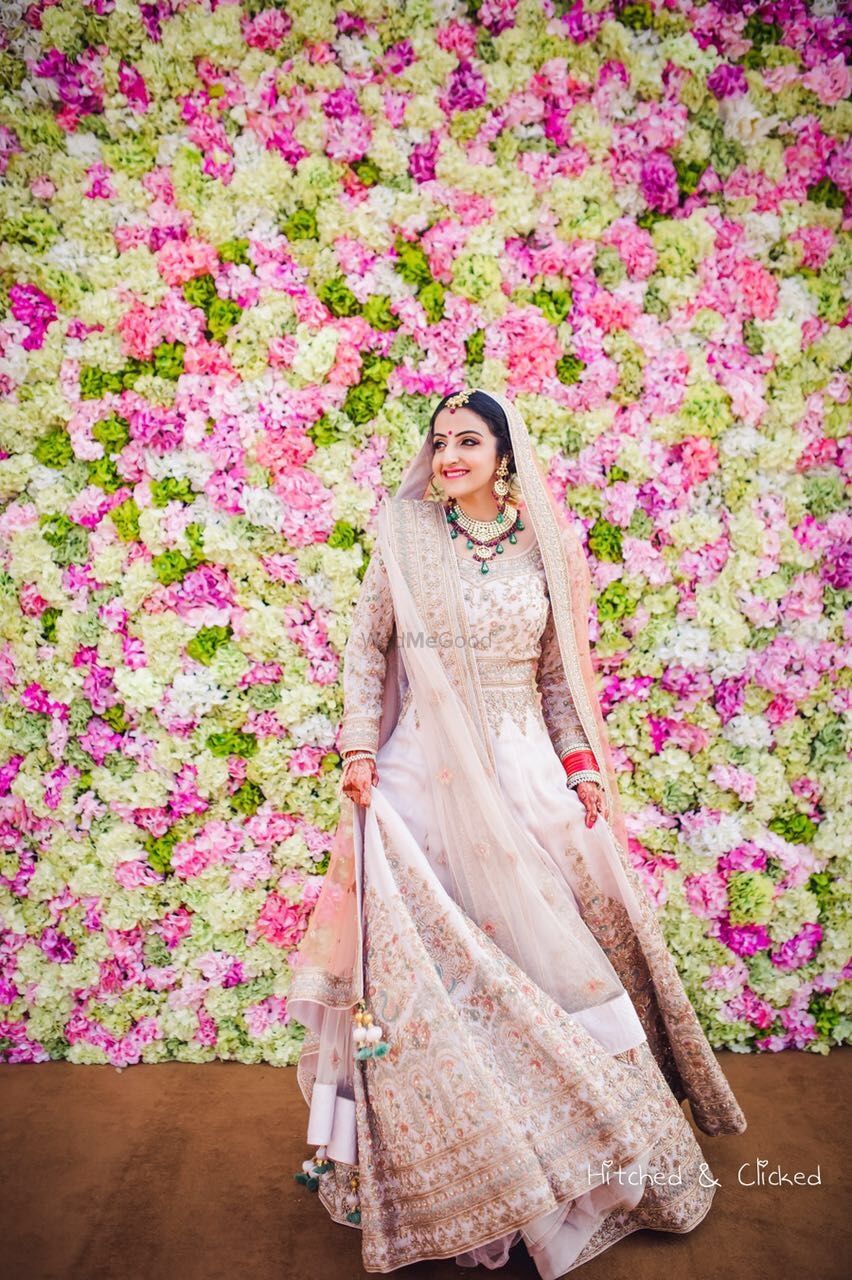 Photo of Bride wearing blush pink Anarkali against floral wall
