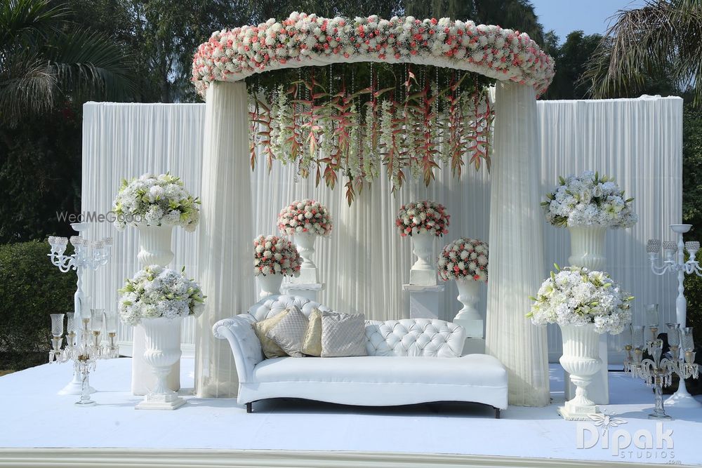 Photo of Elegant stage decor with white drapes and floral arrangements