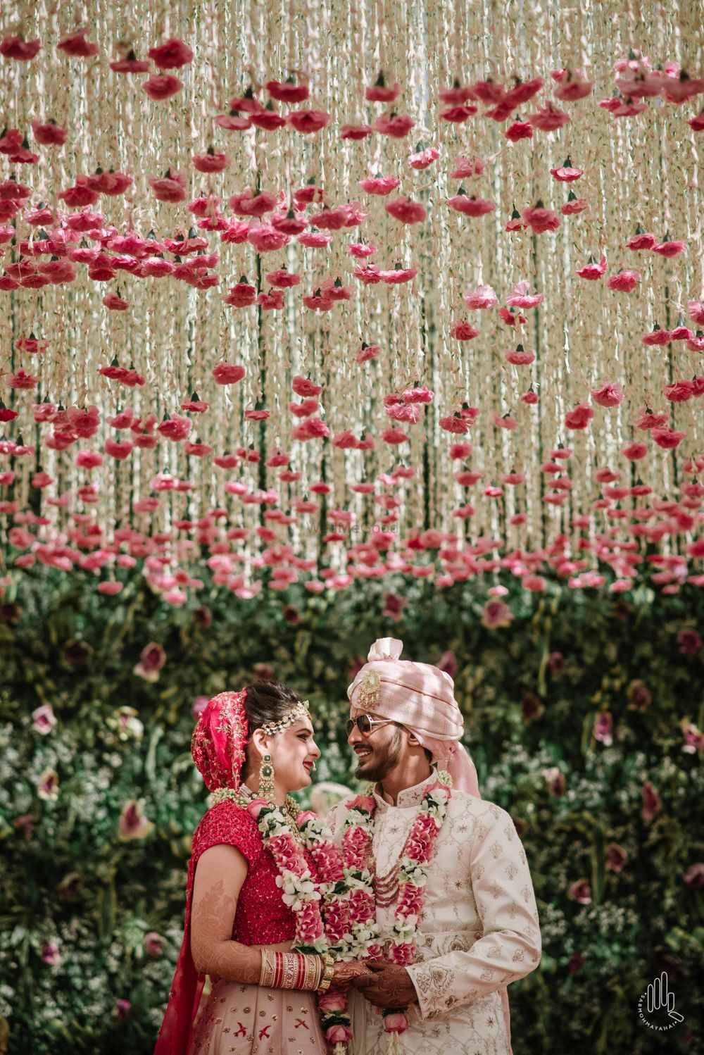 Photo of A couple poses under a floral ceiling on their wedding day