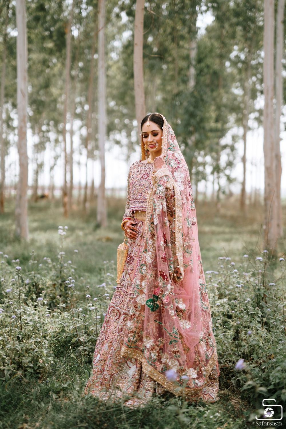 Photo of Bride wearing a fully embellished pink bridal lehenga.