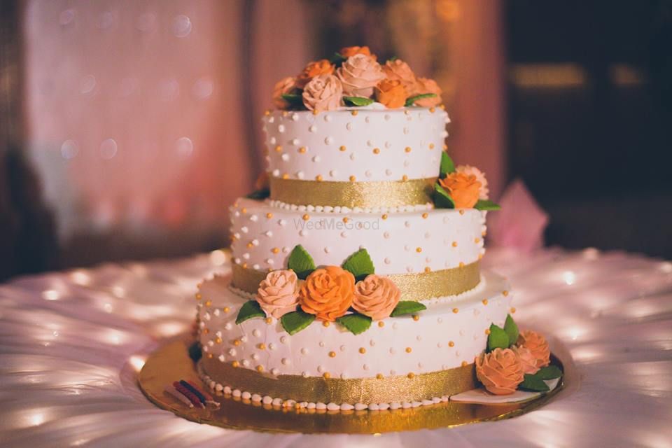 Photo of 3 tiered orange white and gold wedding cake