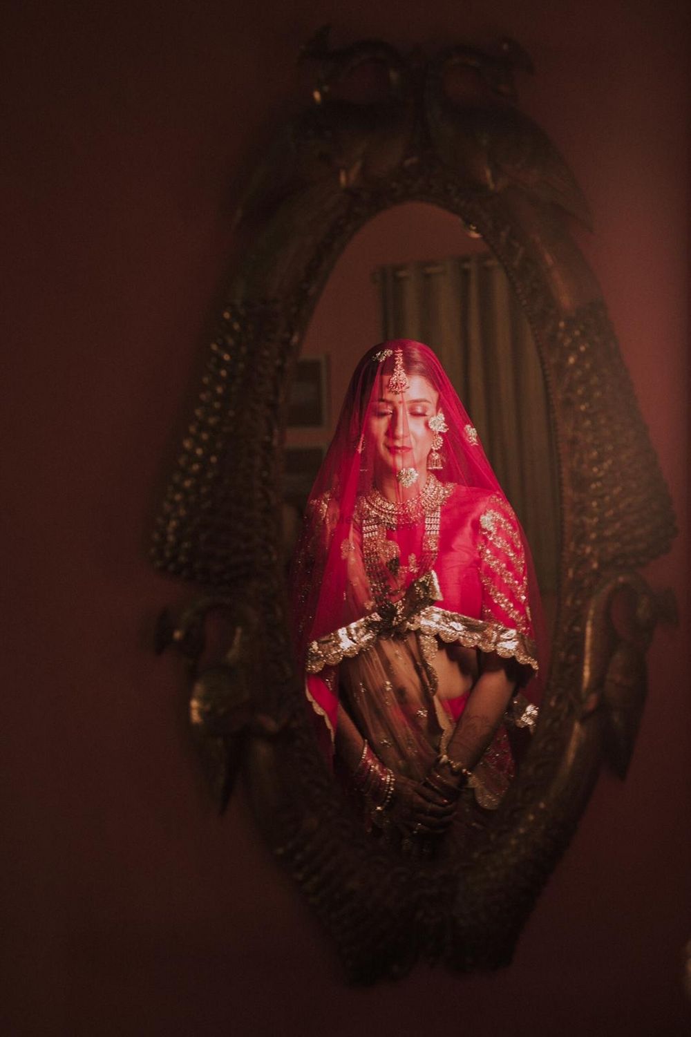 Photo of bride with dupatta as veil getting ready shot