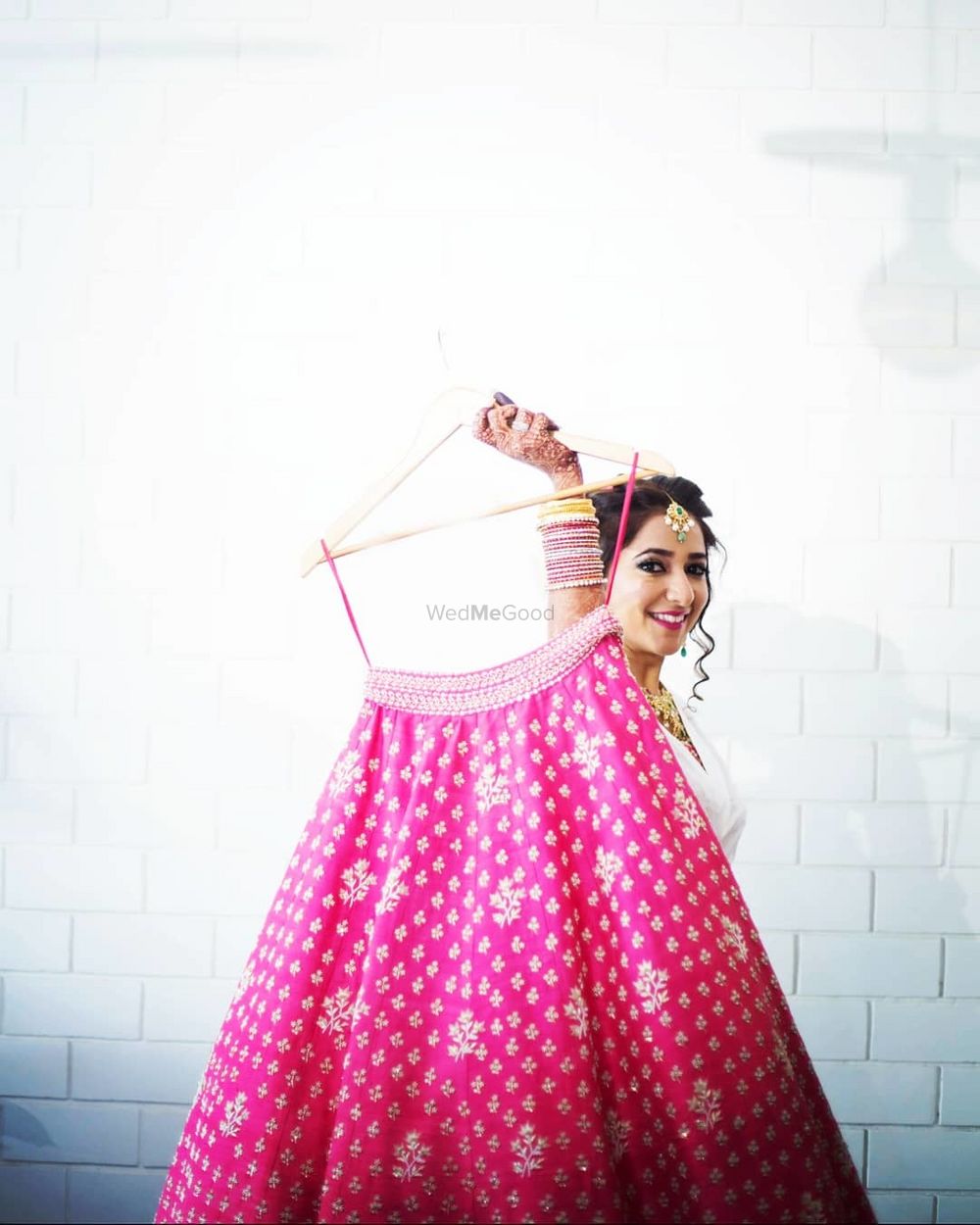 Photo of bride getting ready shot holding up her pink lehenga