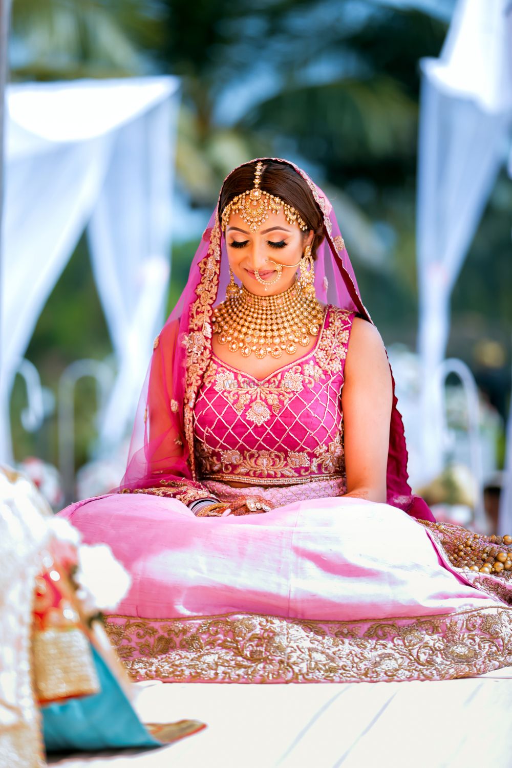 Photo of A bride in pink with gold jewelry on her wedding day