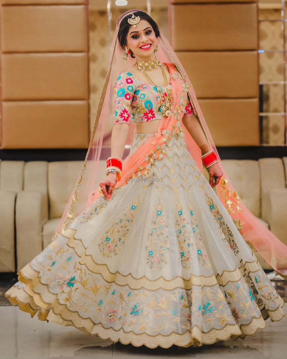 Photo of A bride in white and coral lehenga twirling