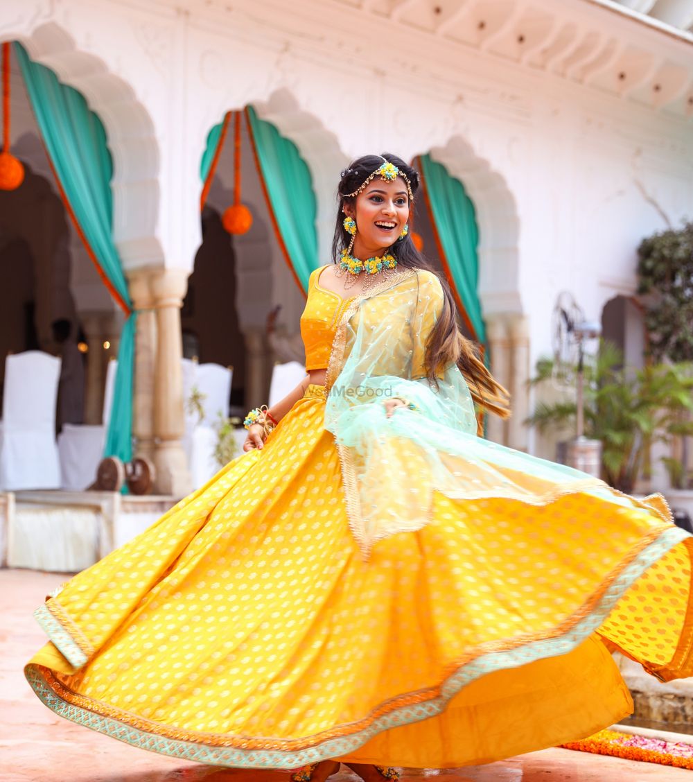Photo of Bride twirling in a bright yellow mango coloured lehenga on her mehendi