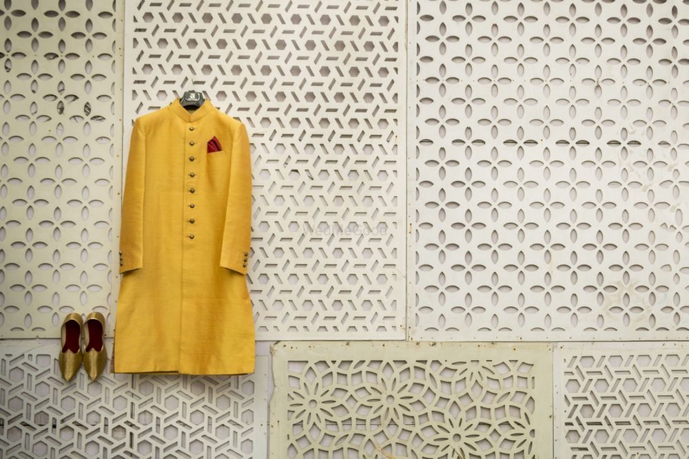 Photo of Sherwani in yellow and shoes on hanger