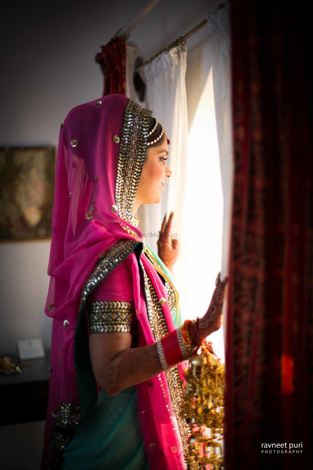 Photo of Bride in green and pink bridal lehenga looking out of window