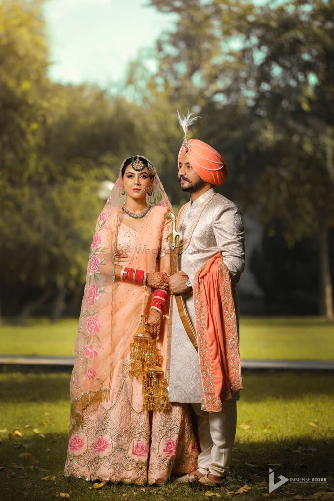 Photo of Matching bride and groom Sikh couple in peach
