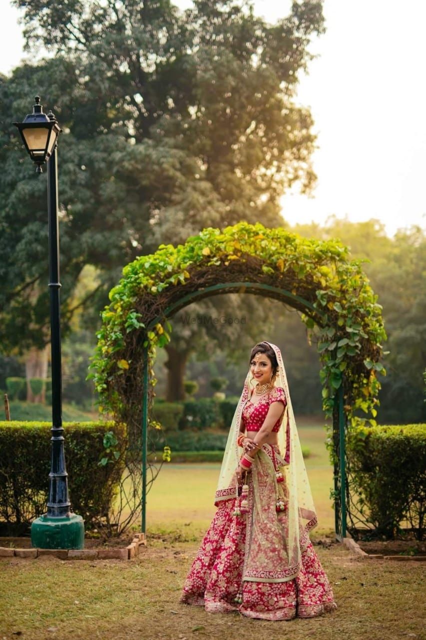 Photo of Bride in red poses on her wedding day in a garden