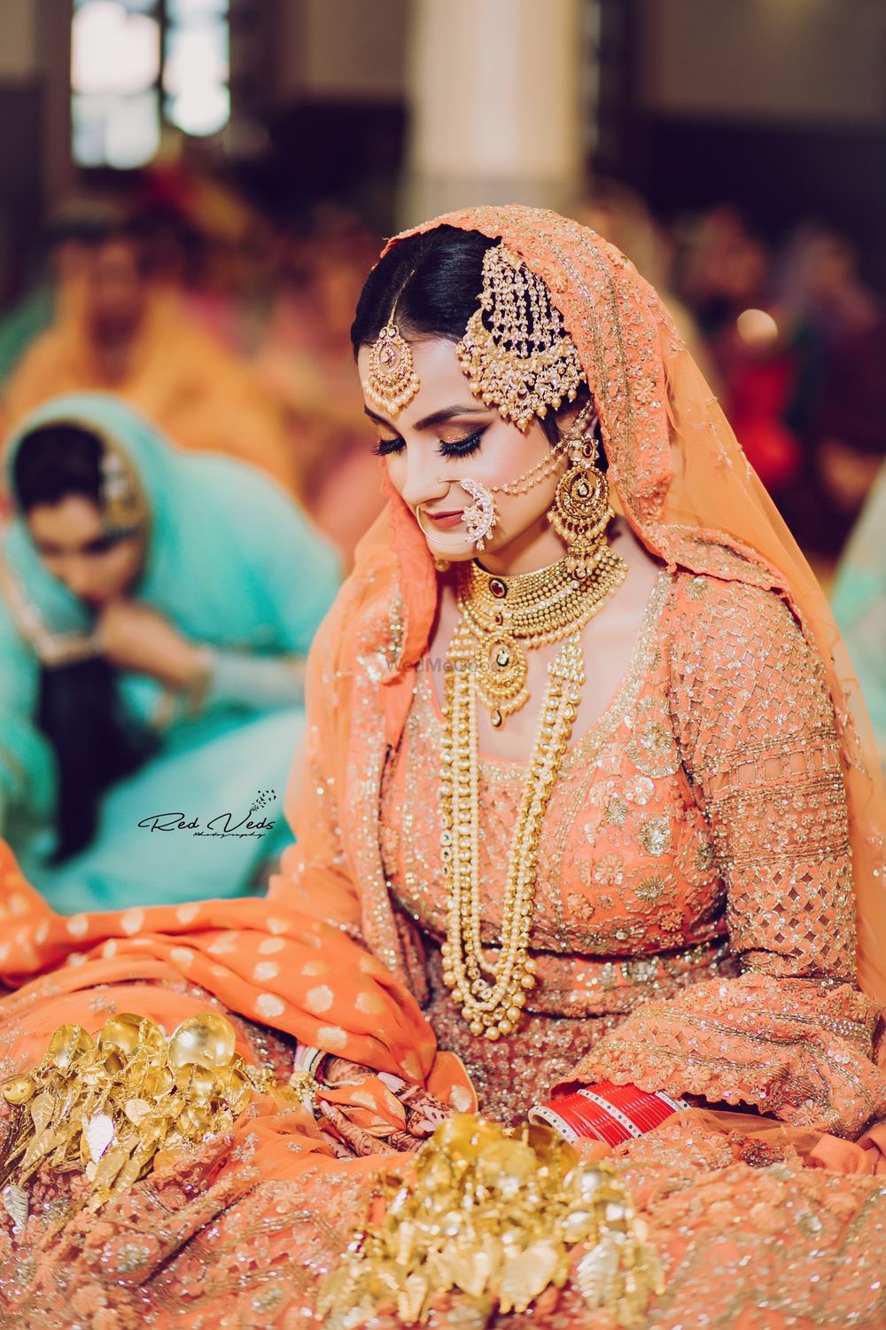 Photo of A bride in orange lehenga and gold jewellery at her Anand Karaj