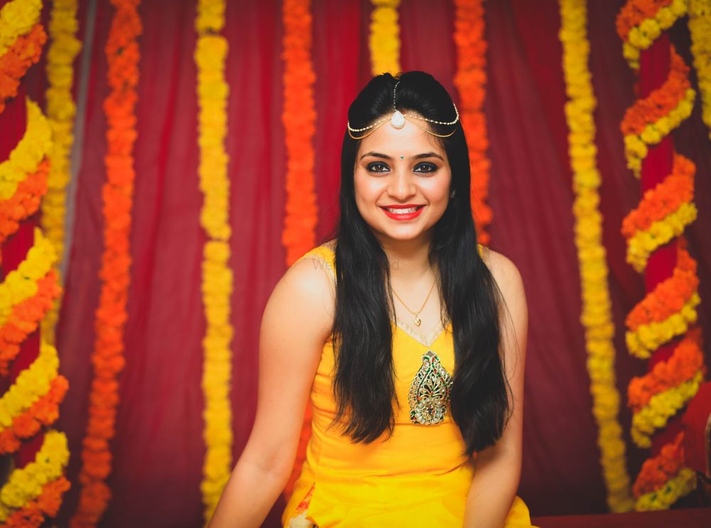 Photo of Bride in yellow kurta and modern mathapatti on mehendi