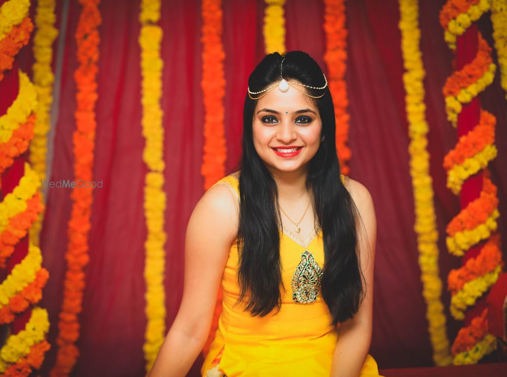 Photo of Bride in yellow kurta and modern mathapatti on mehendi